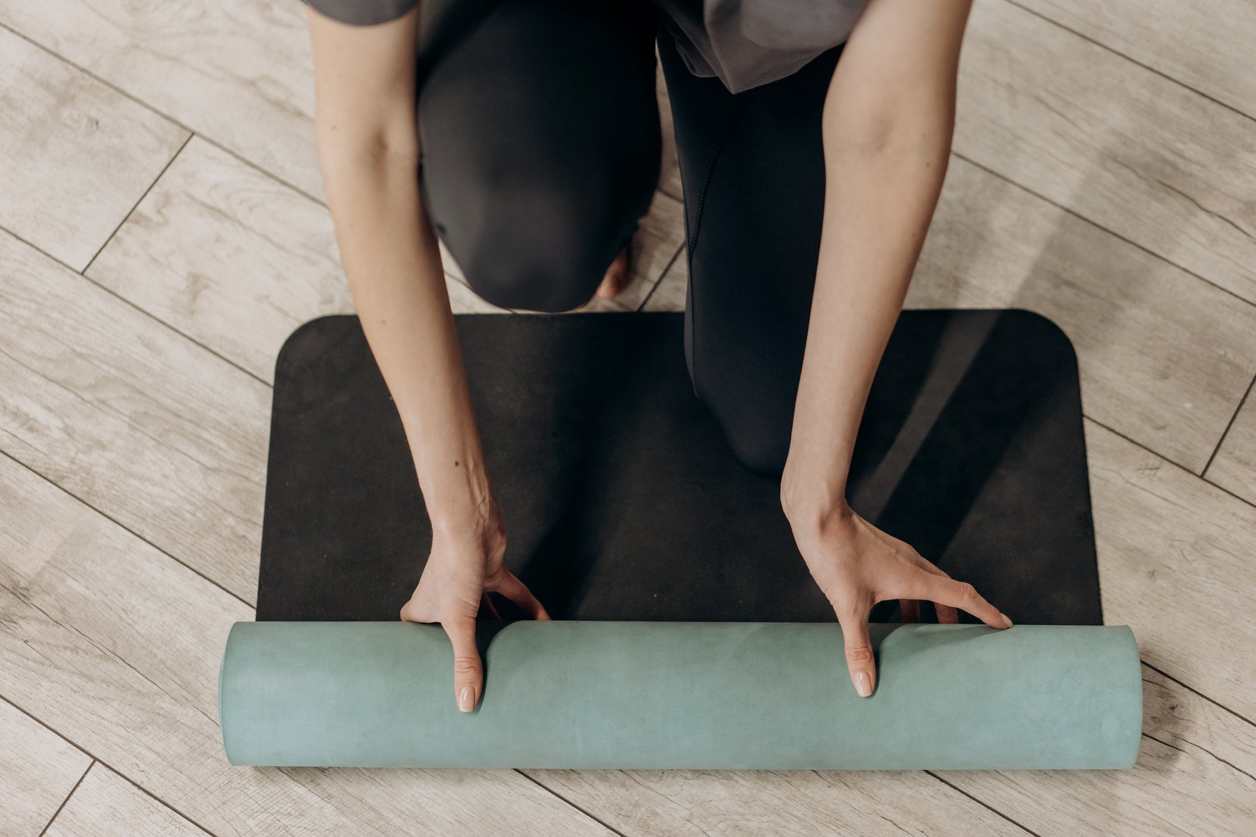 Woman in Black Leggings Unrolling A Yoga Mat